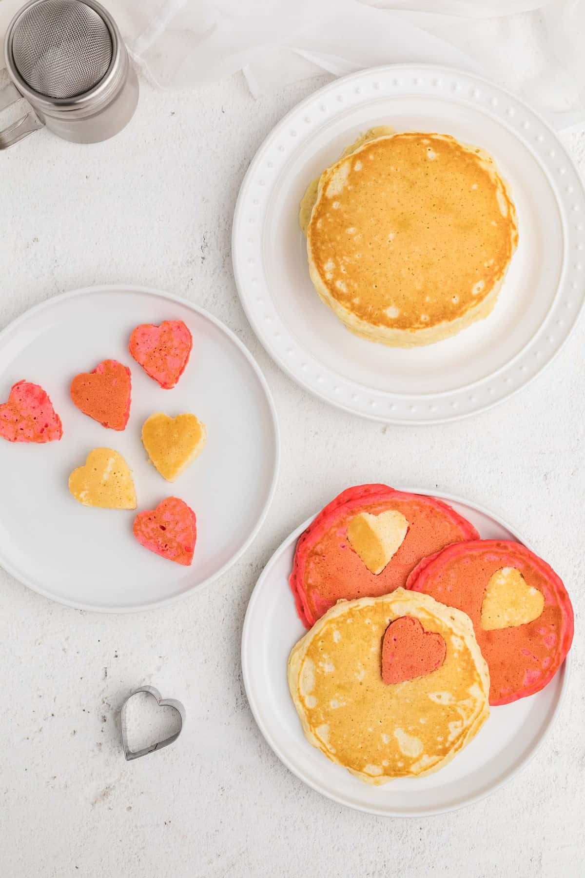 Vue aérienne de pancakes roses et blancs avec des découpes en forme de cœur.