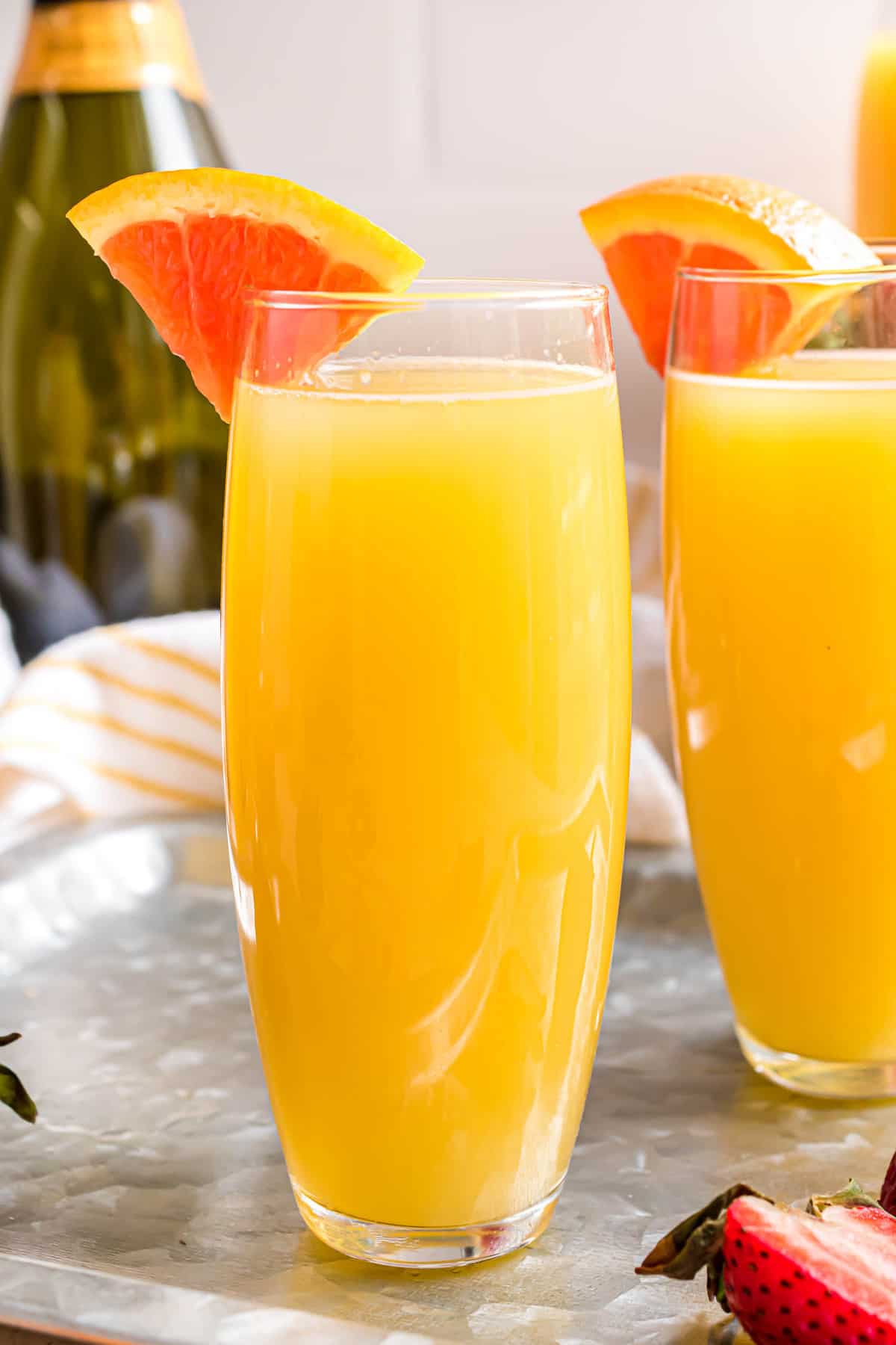 Mimosa à l'orange dans un verre sans pied garni d'un quartier d'orange.