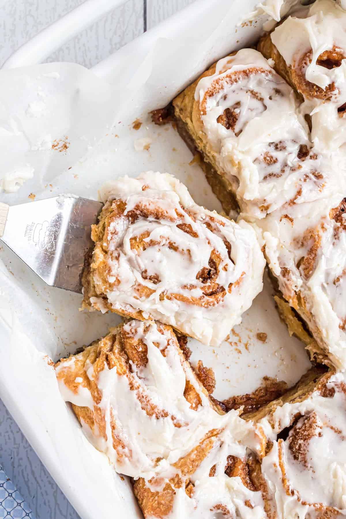Rouleaux de cannelle en pâte feuilletée dans un plat de cuisson blanc.