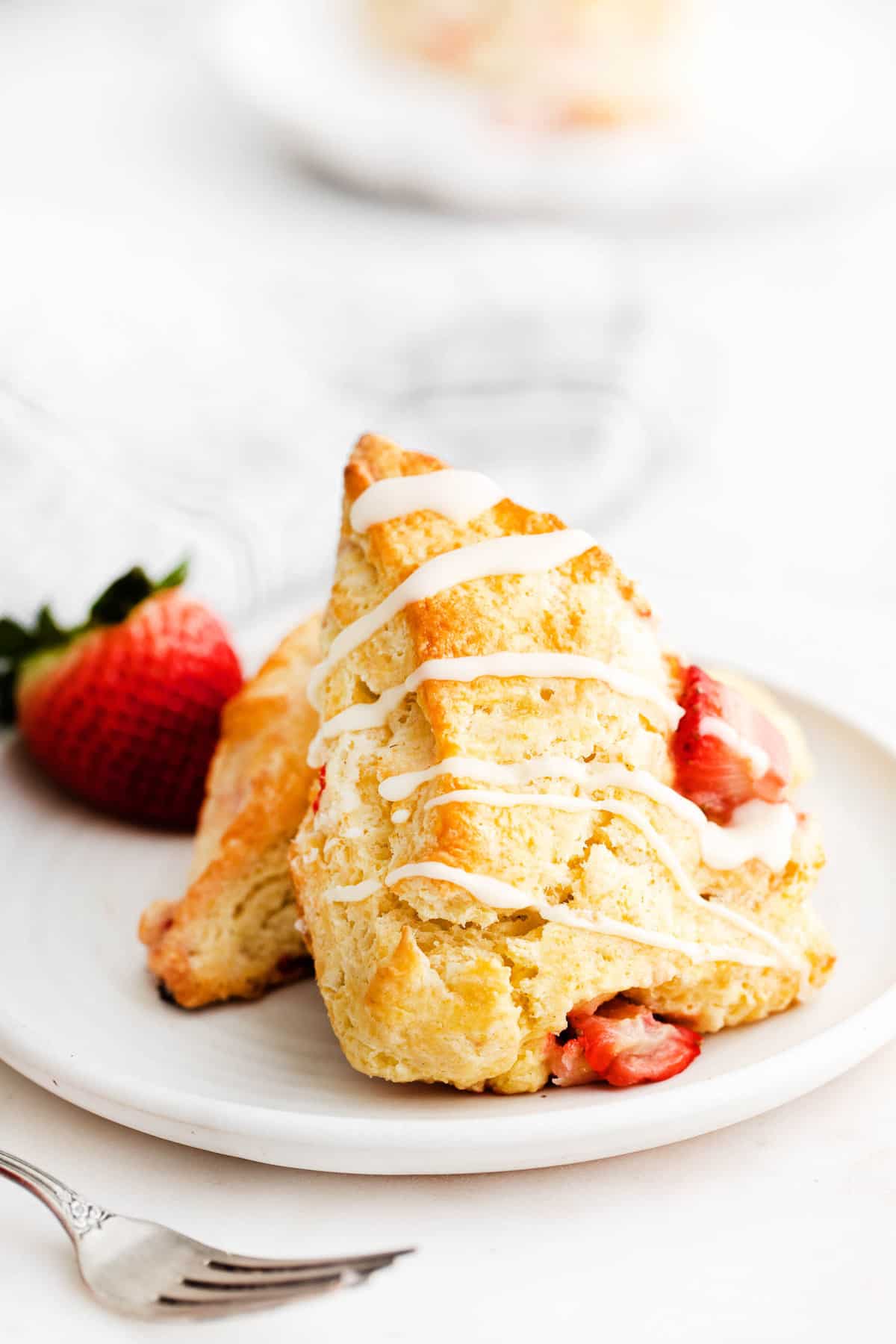 Deux scones aux fraises sur une assiette blanche.