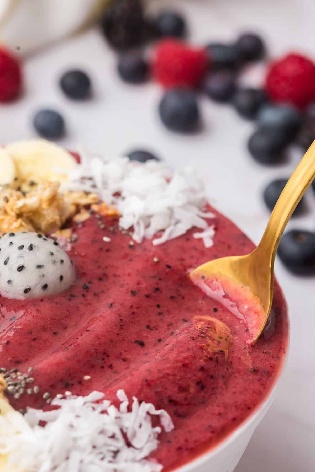Cuillère plongée dans un bol de smoothie aux baies.