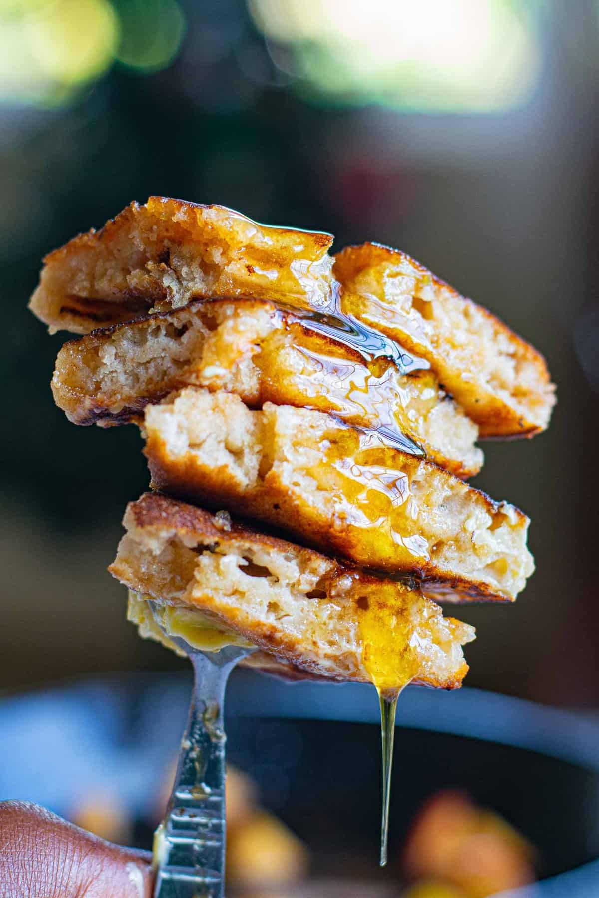 Des pancakes sur une fourchette avec du sirop qui coule.