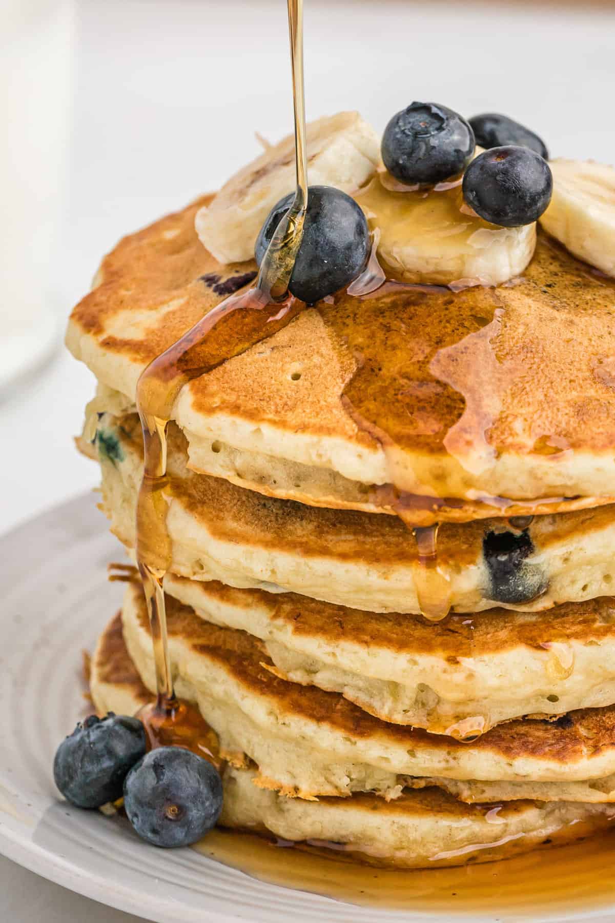 Pancakes aux bananes et myrtilles arrosés de sirop.