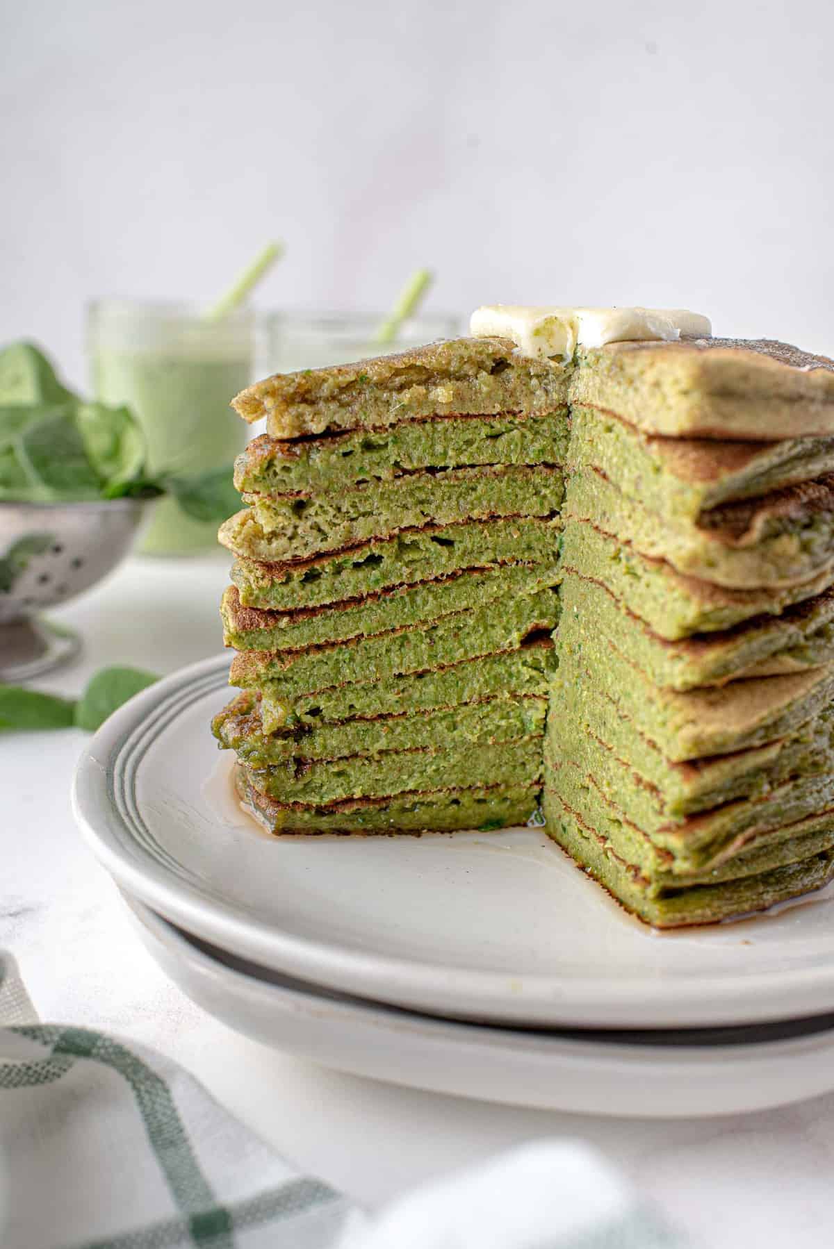 Empilement de pancakes de smoothie vert avec une part découpée pour montrer la texture et la couleur.