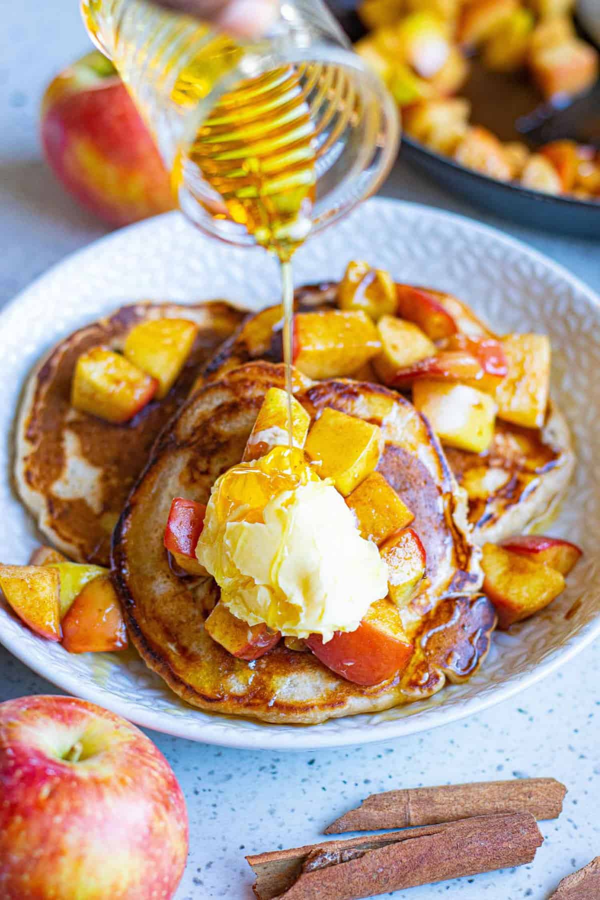 Du sirop versé sur des pancakes aux pommes véganes.