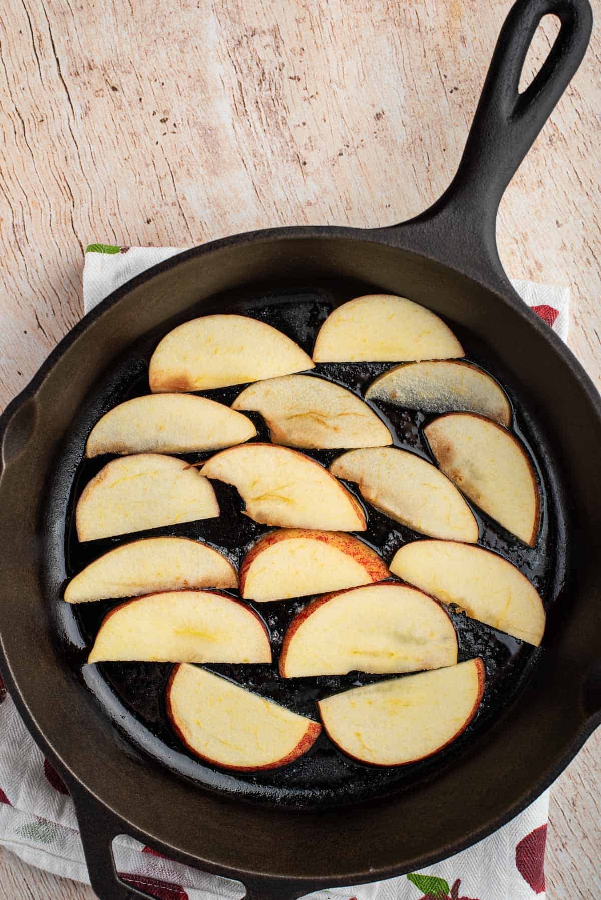 Pommes tranchées au fond d'une poêle noire.