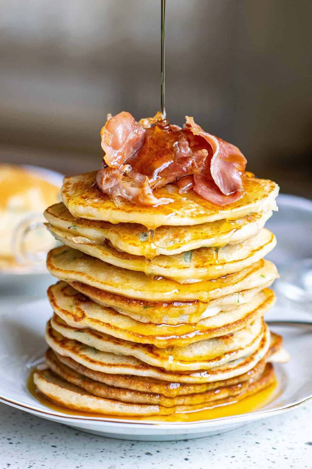 Du sirop versé sur une pile de pancakes au bacon.