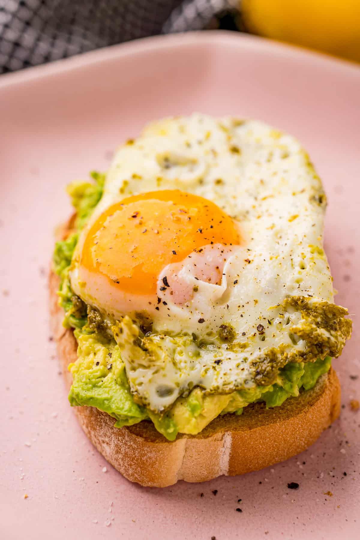 Gros plan d'un œuf au pesto sur une assiette.