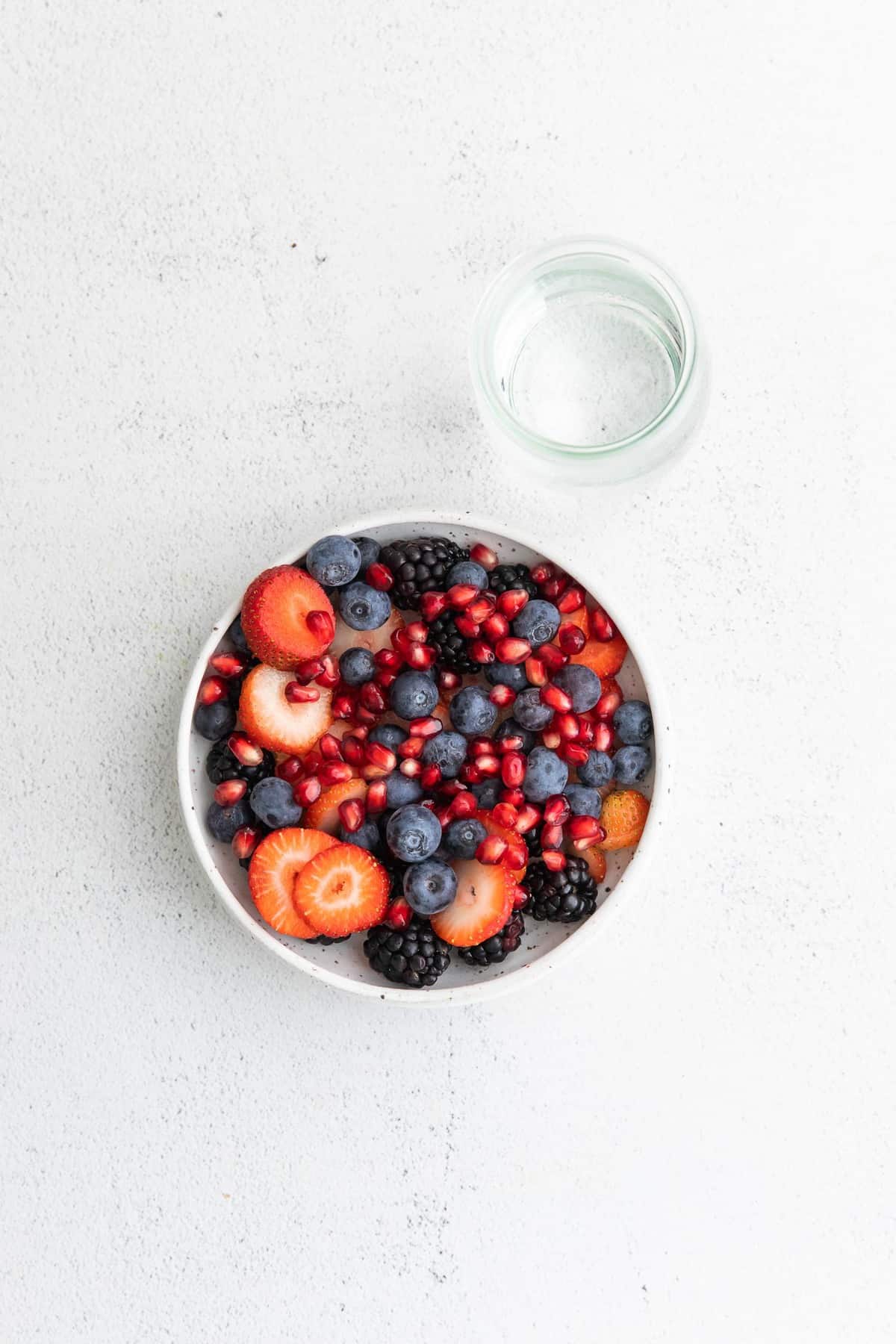 Des fruits dans un bol avec un verre d'eau de coco à côté.