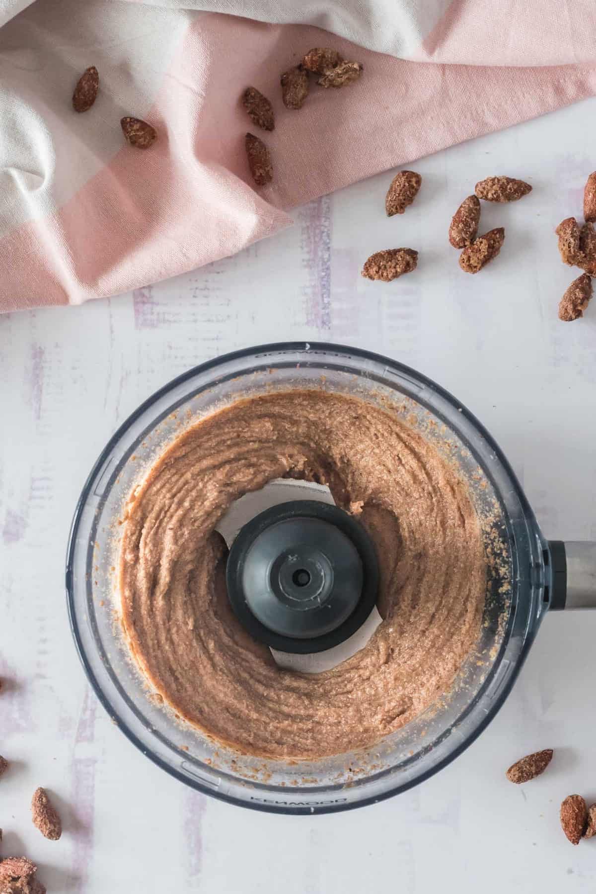 Beurre d'amande partiellement mélangé dans un robot culinaire.