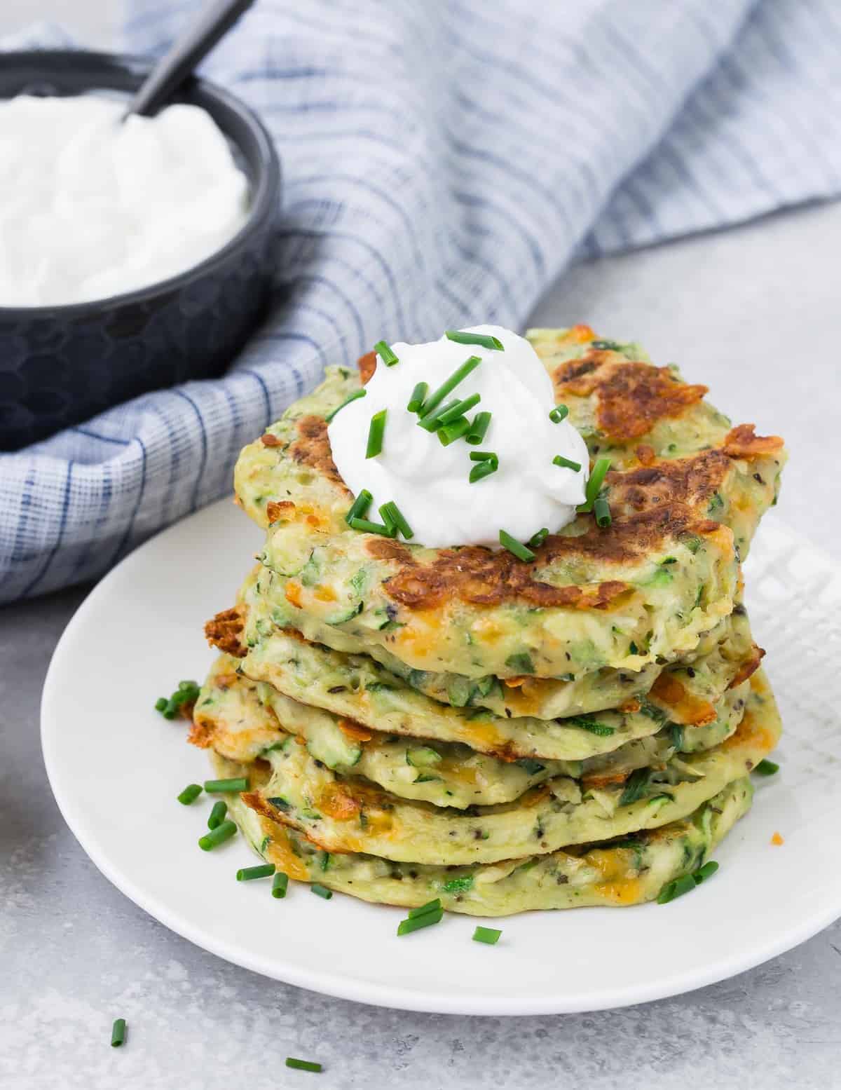 Des beignets de courgettes empilés sur une assiette blanche.