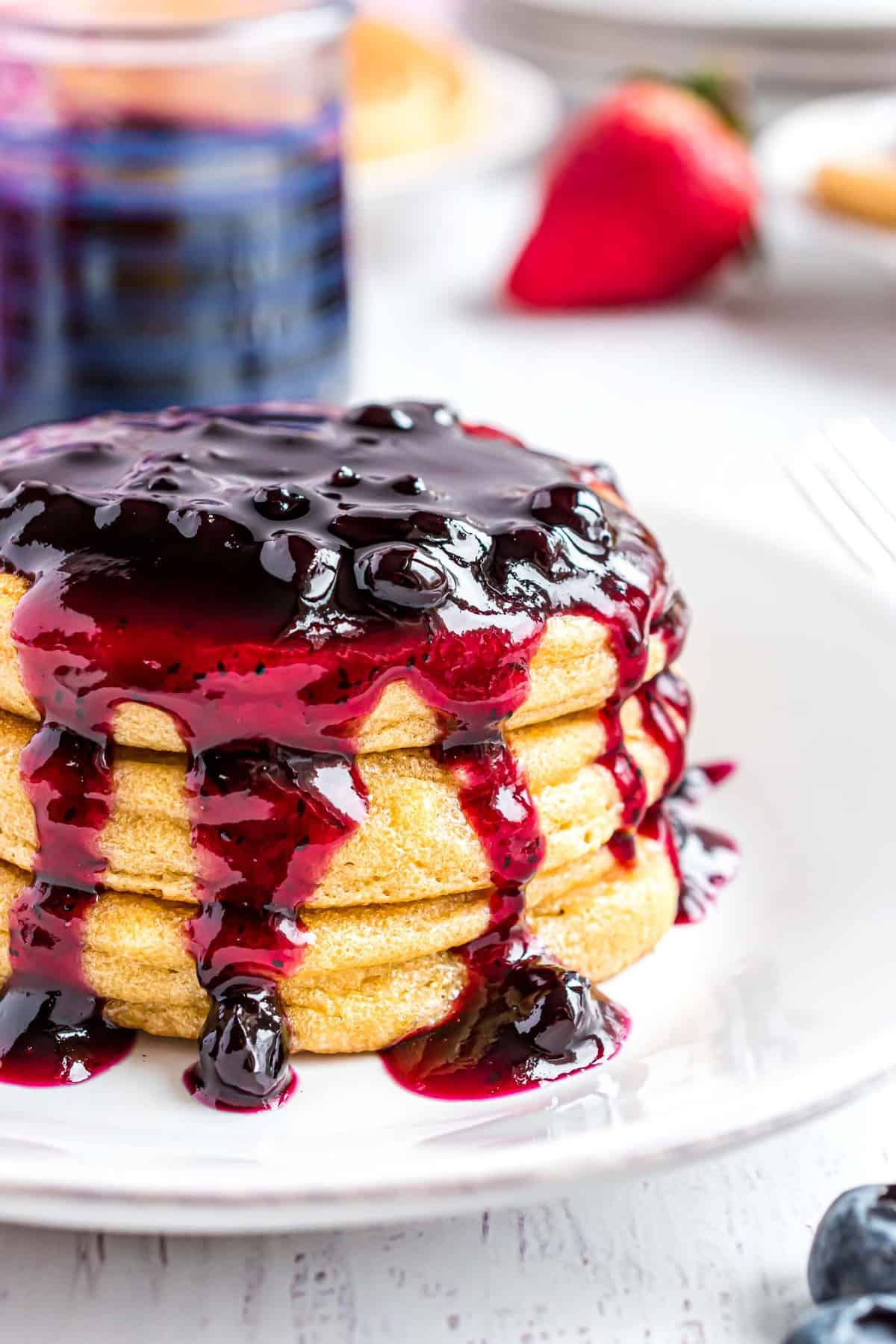Pile de pancakes dégoulinant de sauce aux myrtilles.