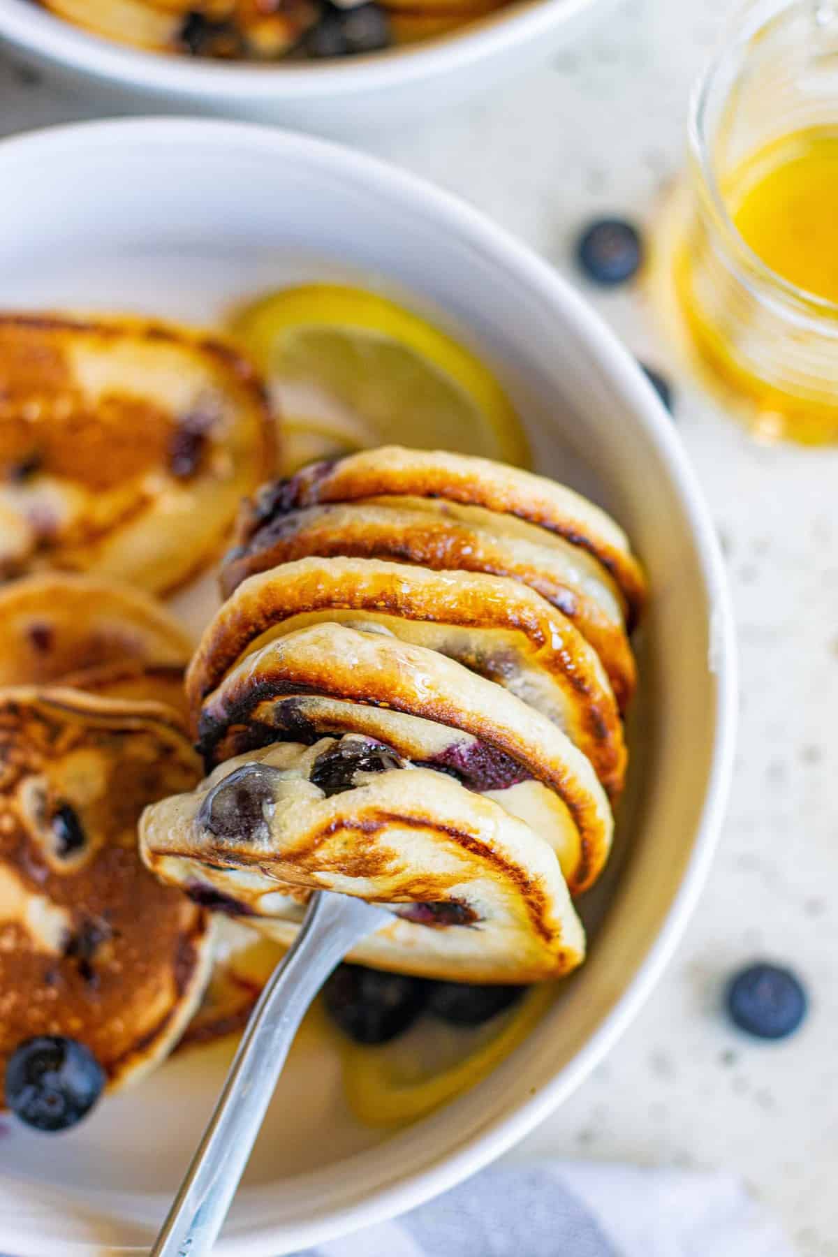 Grosse pile de petits pancakes sur une fourchette.