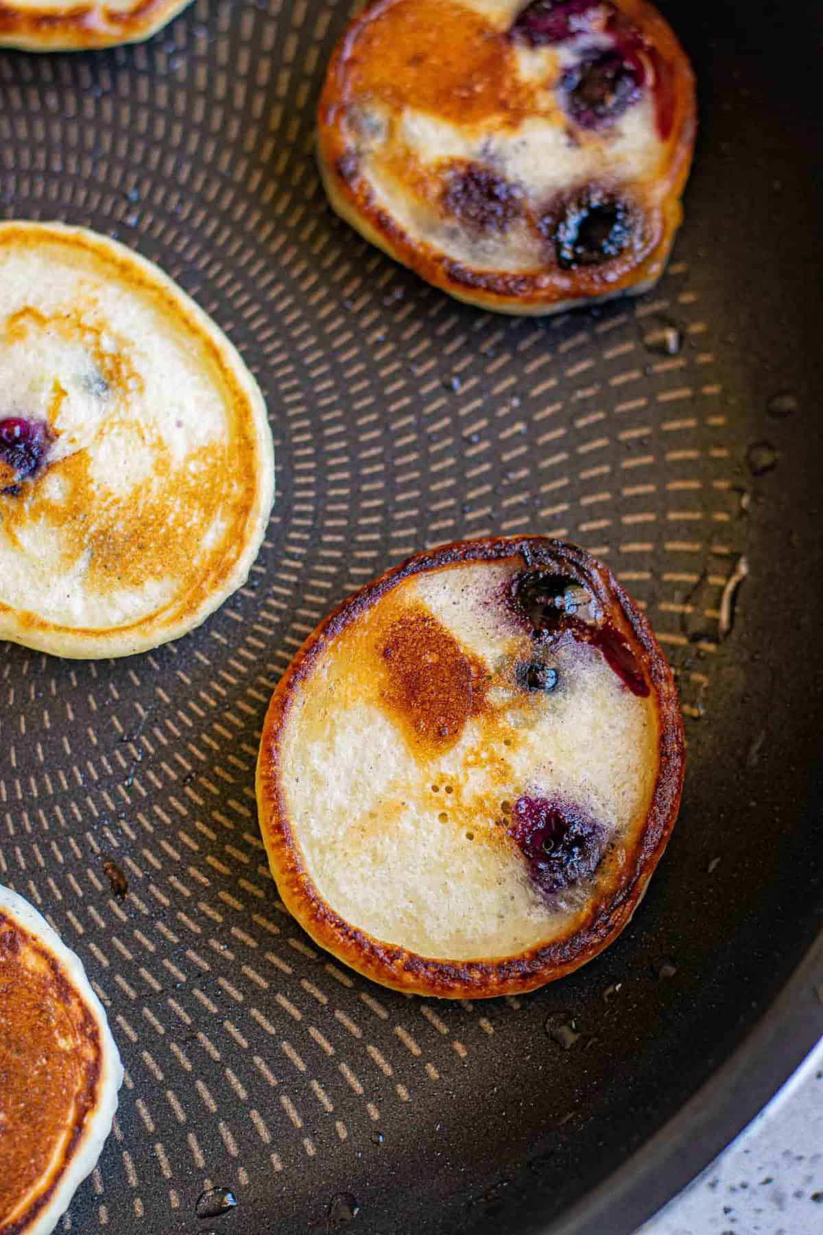 Pancakes miniatures parfaitement cuits dans une poêle.