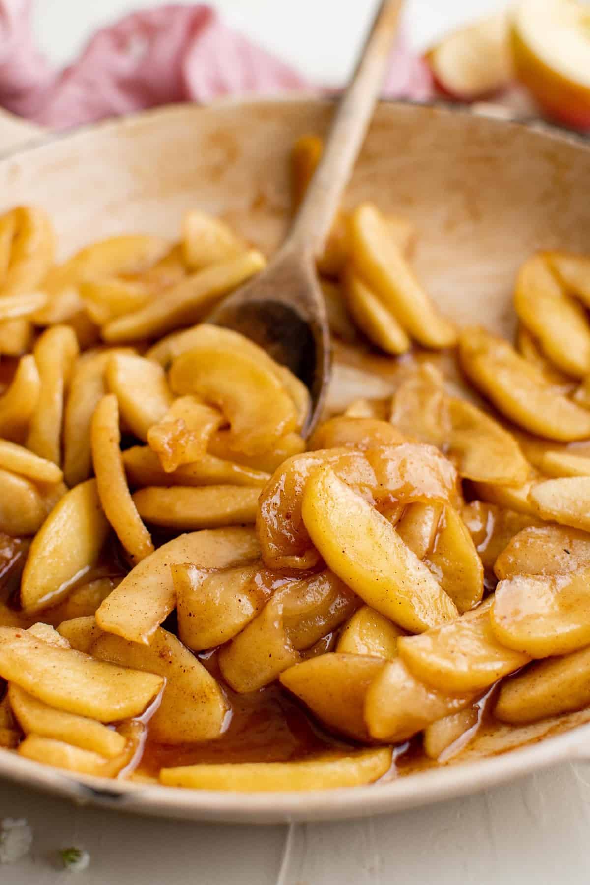 Pommes cuites dans une poêle avec une cuillère en bois.