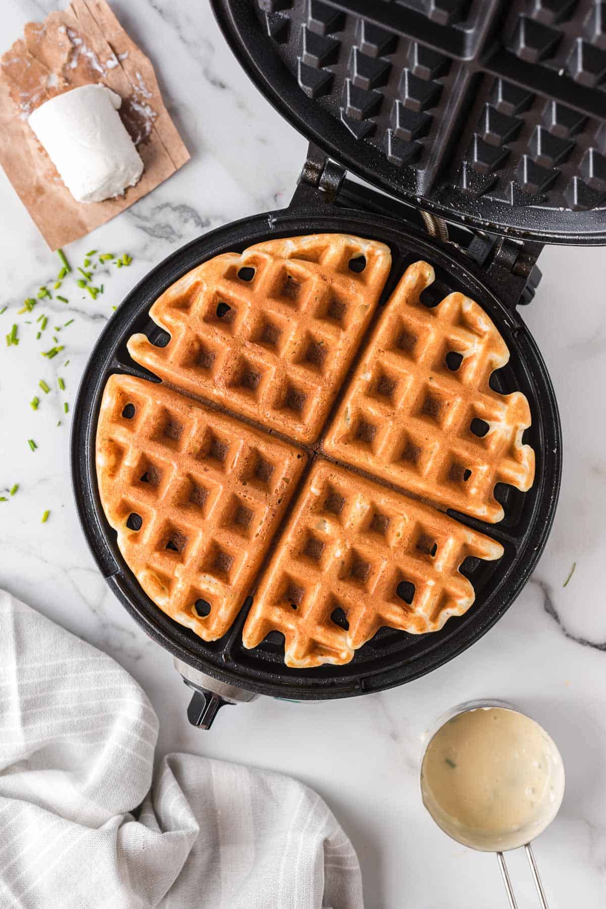 Vue aérienne d'une gaufre dans un gaufrier, entourée d'ingrédients.