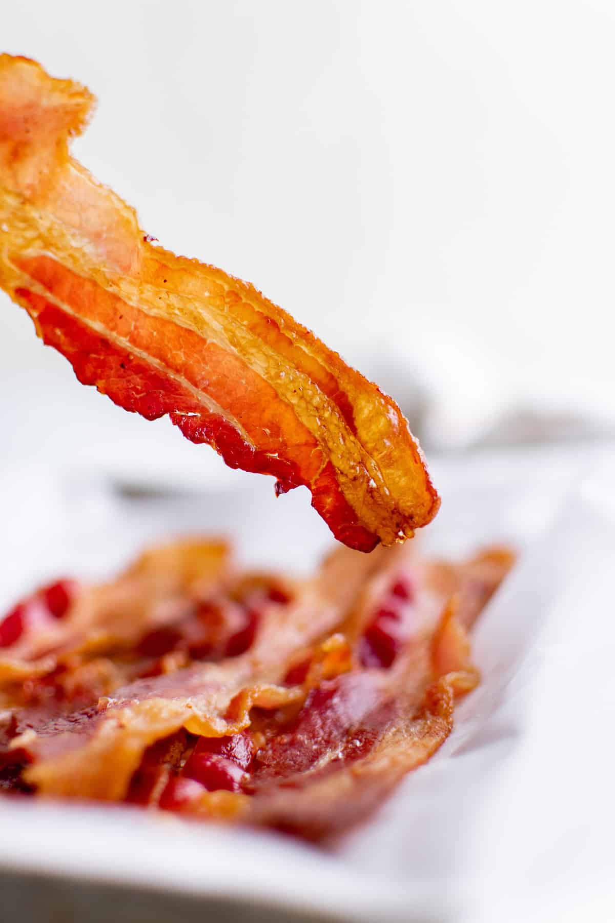 Morceau de bacon croustillant tenu pour montrer sa texture.