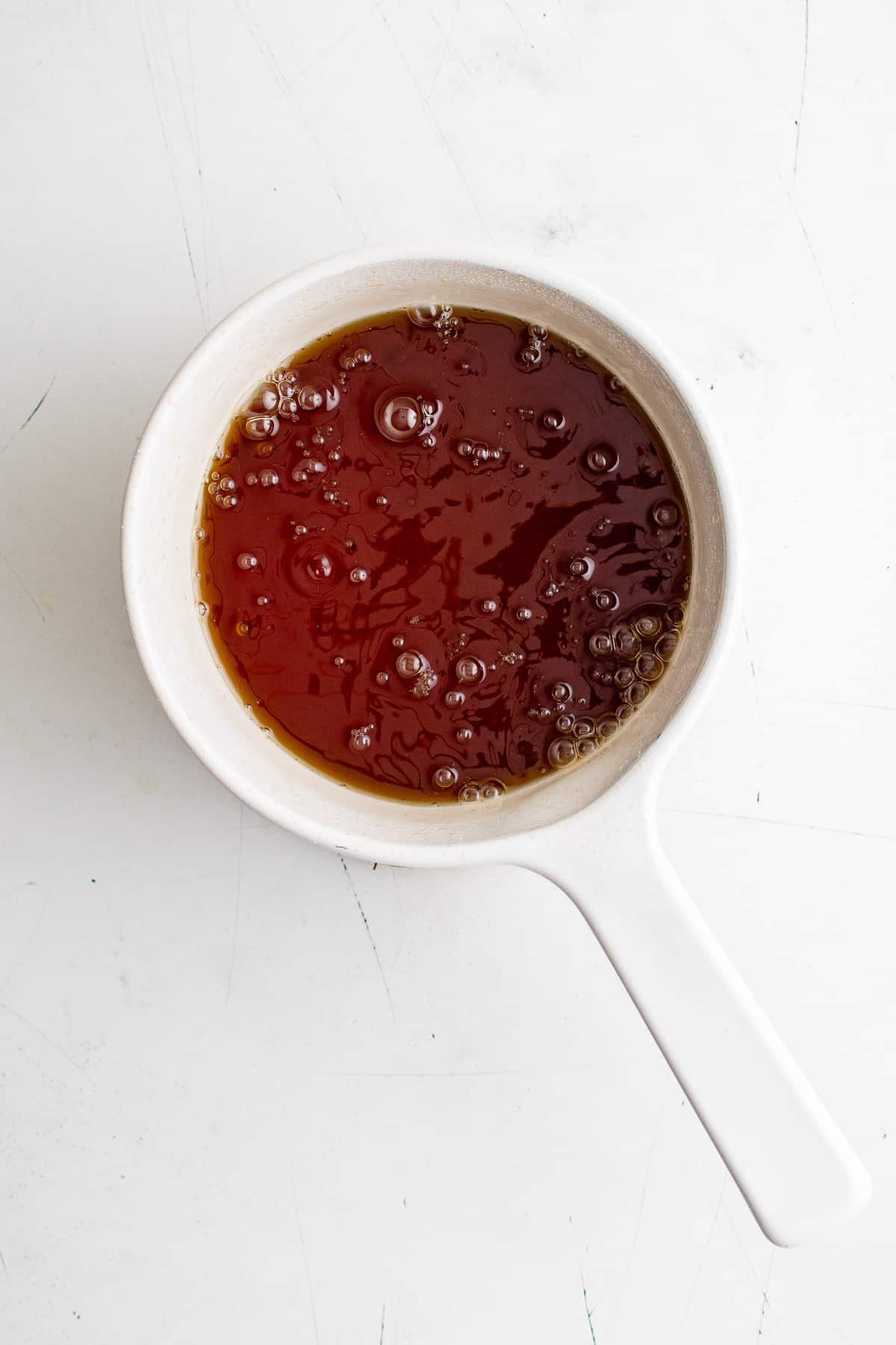 Sirop pour pancakes en cours de cuisson, dans une casserole blanche.