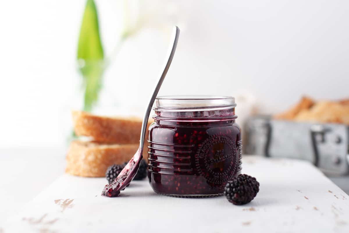Confiture sombre avec une cuillère usagée posée contre le pot.