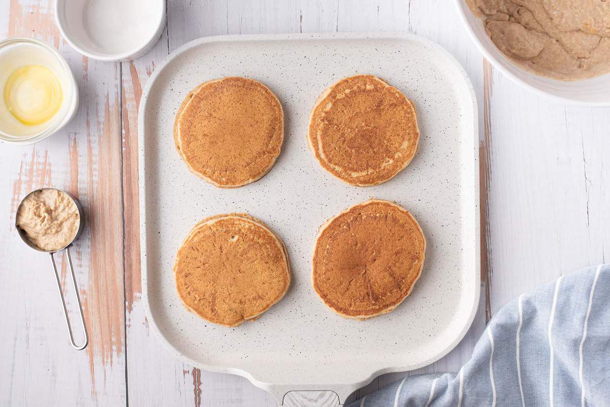 Pancakes cuits sur une poêle blanche.