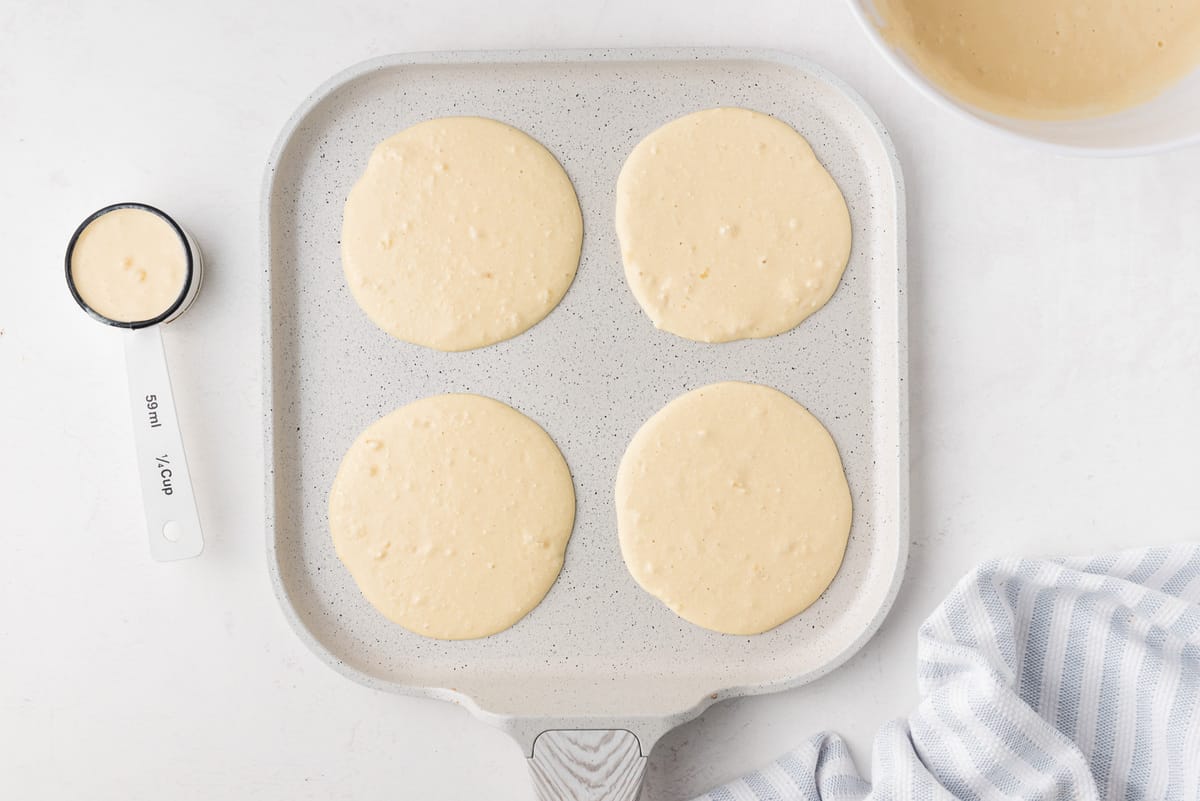 Pancakes non cuits sur une poêle blanche.