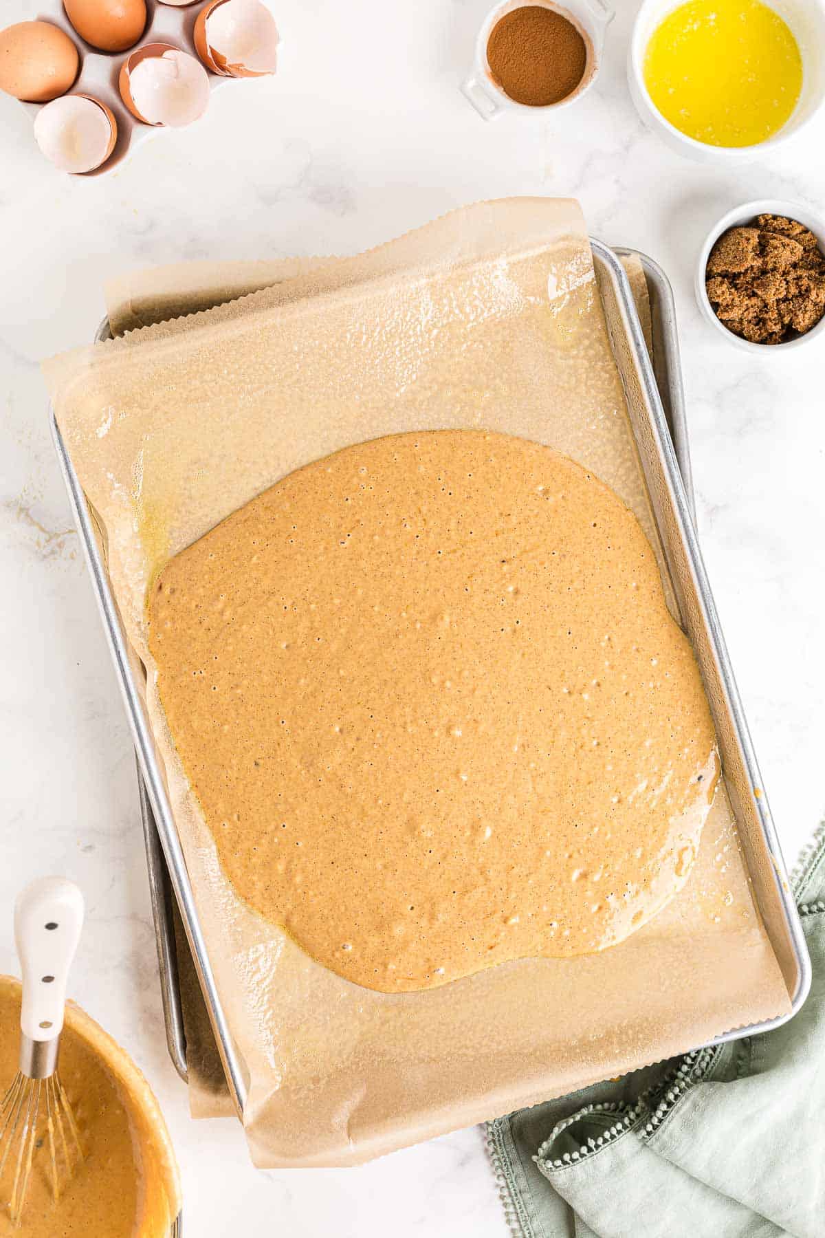 Pâte versée dans une plaque de cuisson tapissée de papier sulfurisé.