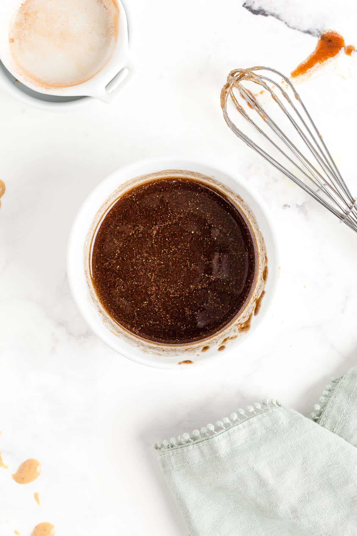 Coulis de beurre à la cannelle dans un bol blanc. Un fouet est aussi visible.