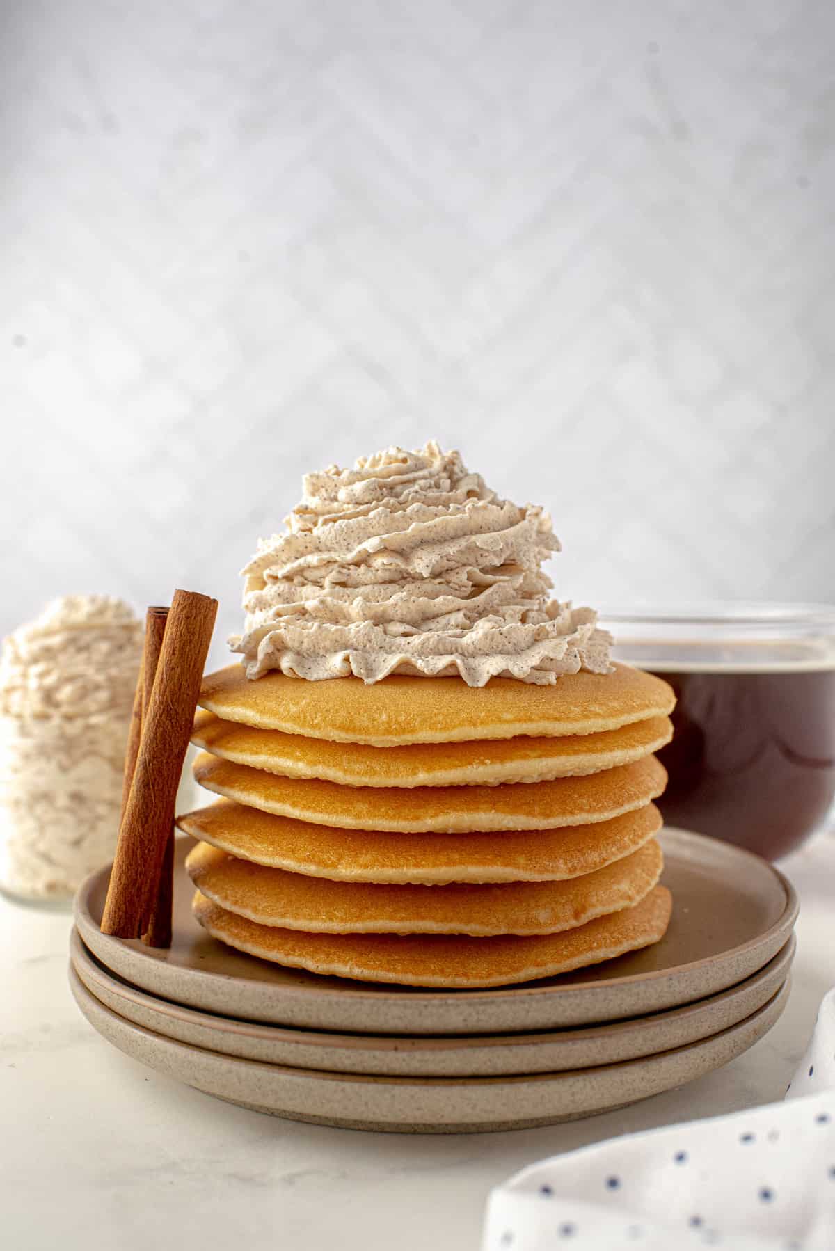 Pile de pancakes garnis de crème fouettée.