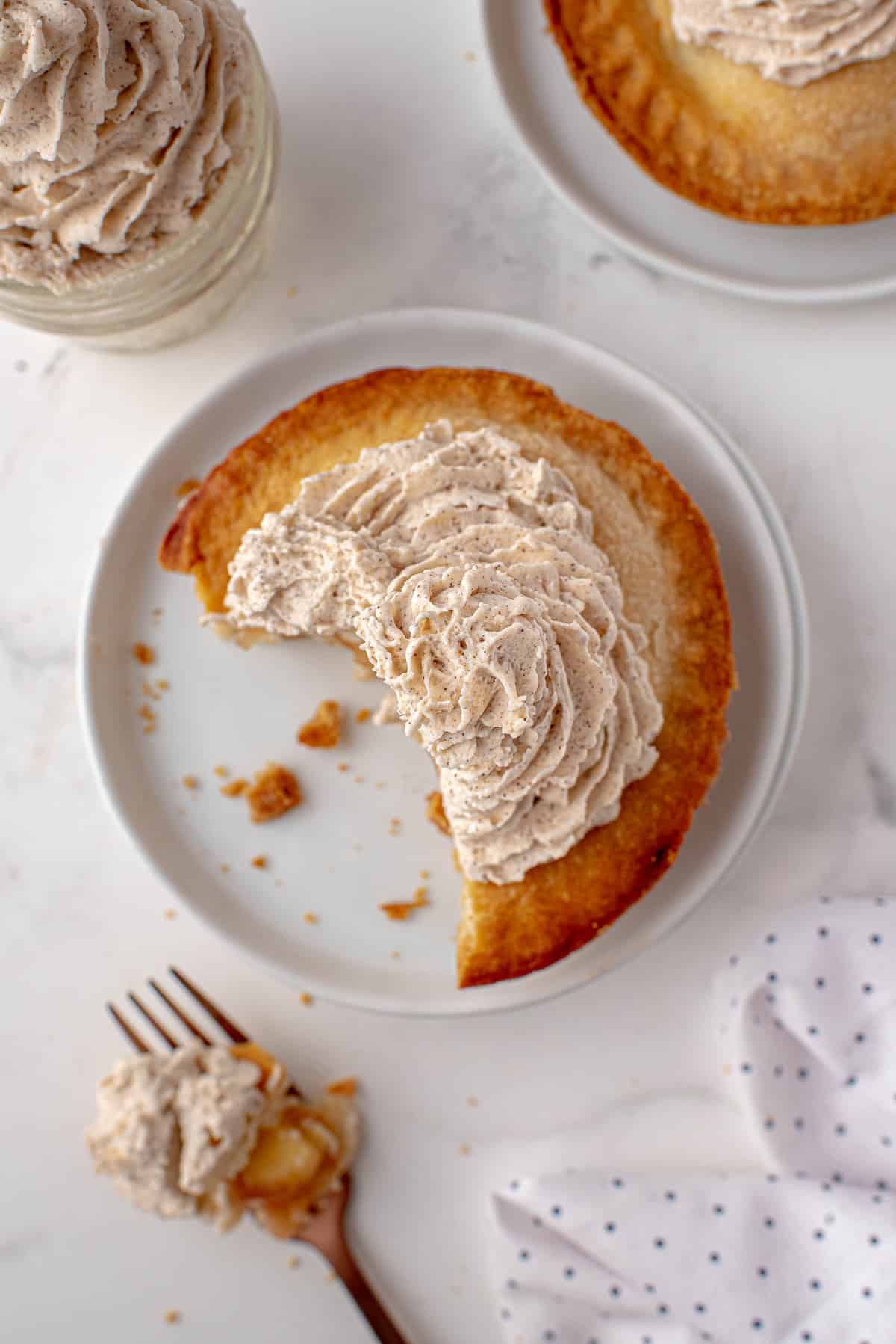 Tarte aux pommes individuelle sur une assiette blanche, garni de crème fouettée.