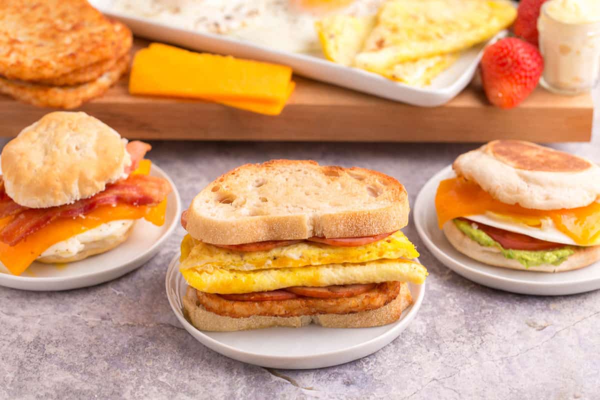 Trois différents sandwiches aux œufs sur de petites assiettes blanches.
