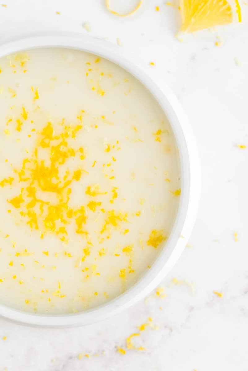Glaçage dans un petit bol blanc, saupoudré de zeste de citron.