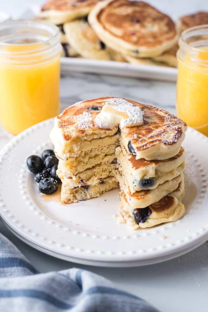 Pile de pancakes avec une tranche retirée pour montrer la texture et les myrtilles à l'intérieur.