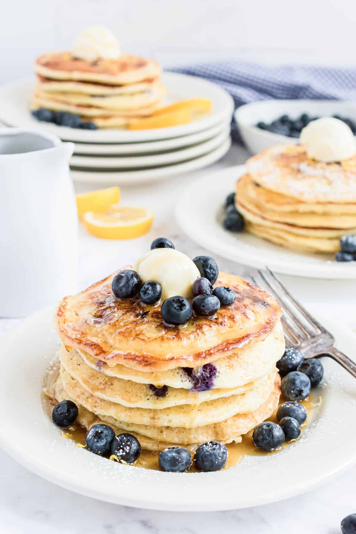 Pancakes empilés, garni d'une boule de beurre, de myrtilles et de sirop.