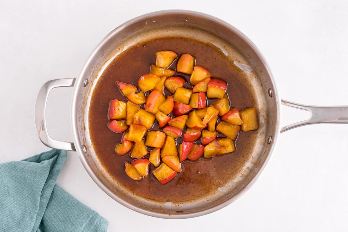 Morceaux de pommes à la cannelle dans une sauce de sucre brun, dans une poêle.