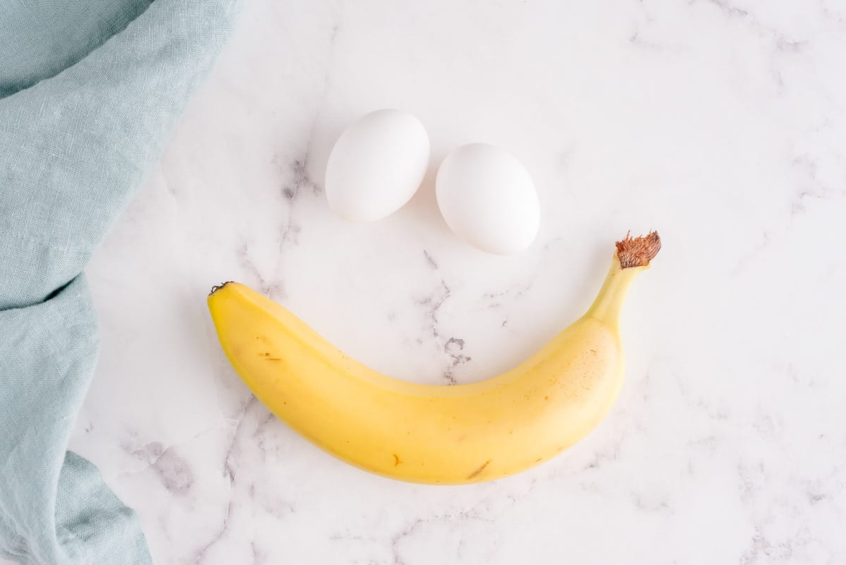 Deux œufs et une banane sur un fond en marbre.