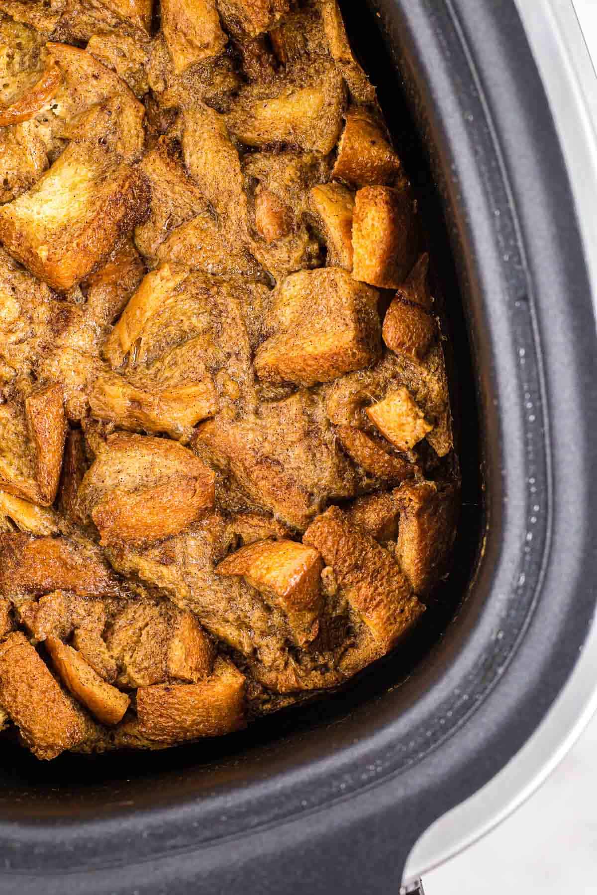 Gros plan sur la casserole de pain perdu dans une mijoteuse noire.