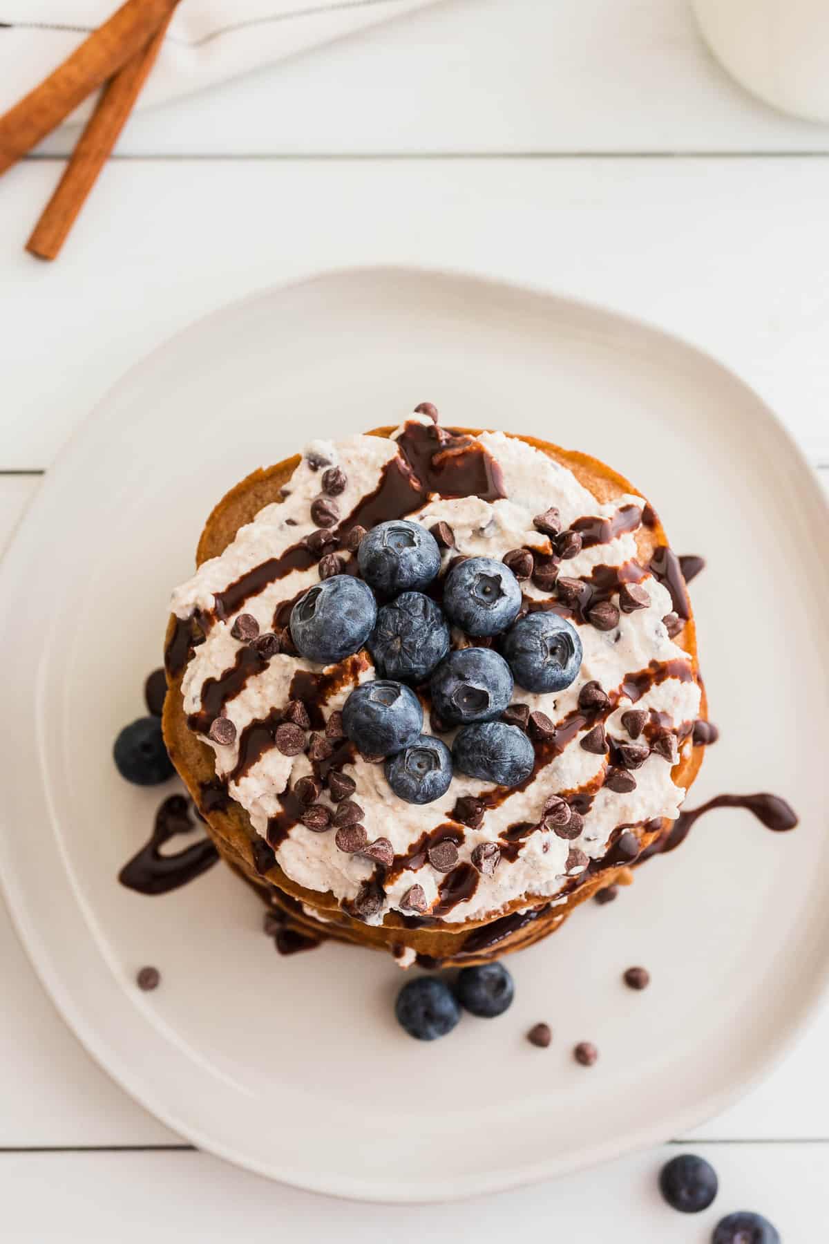 Vue aérienne d'une pile de pancakes garnis de myrtilles et de pépites de chocolat.