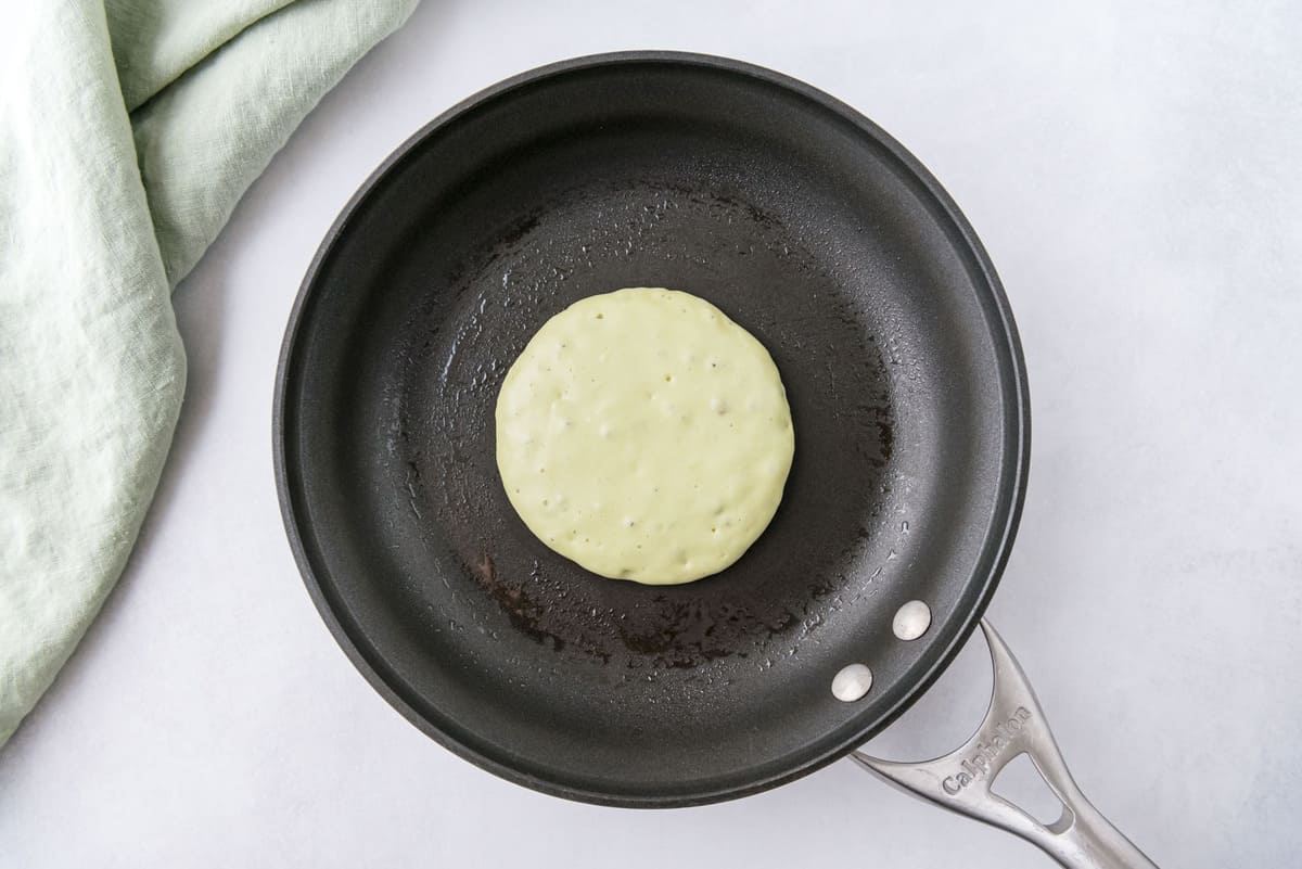 Pancake vert clair non cuit dans une poêle noire.
