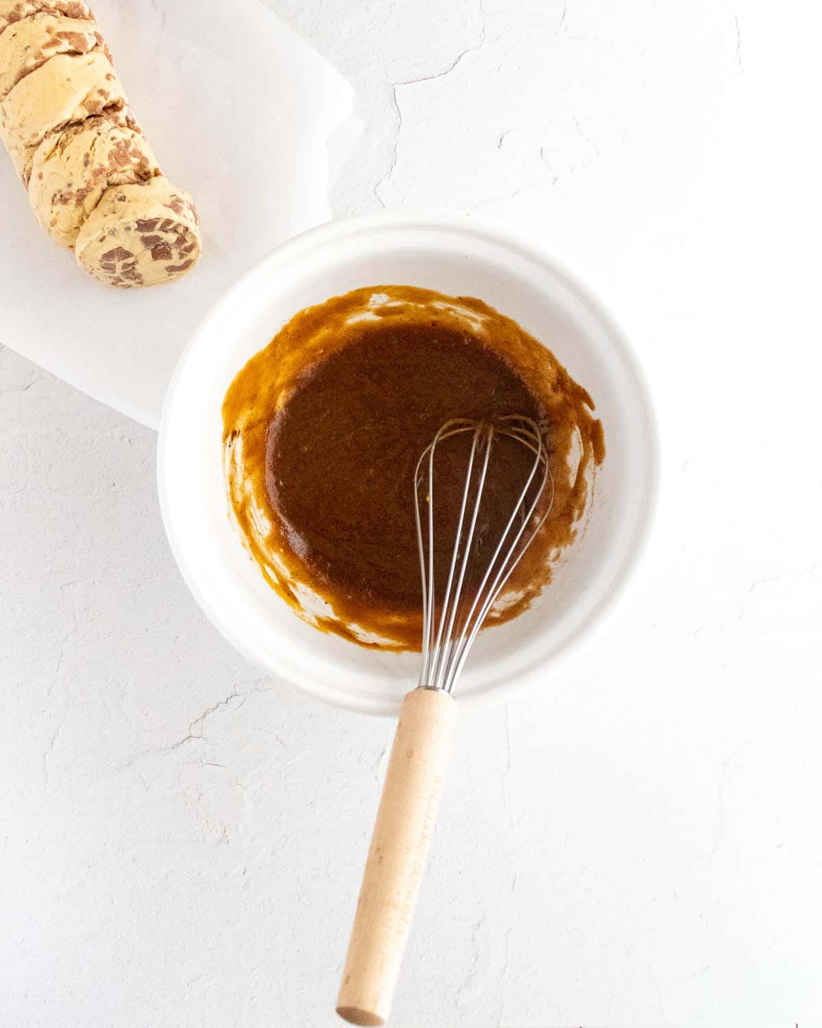 Purée de citrouille mélangée avec du beurre, du sucre brun et des épices dans un bol blanc avec un fouet.
