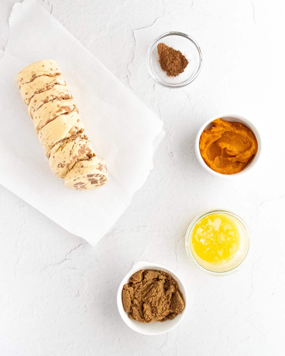 Vue aérienne des ingrédients nécessaires pour les muffins de pain de singe à la citrouille, sur un fond blanc.