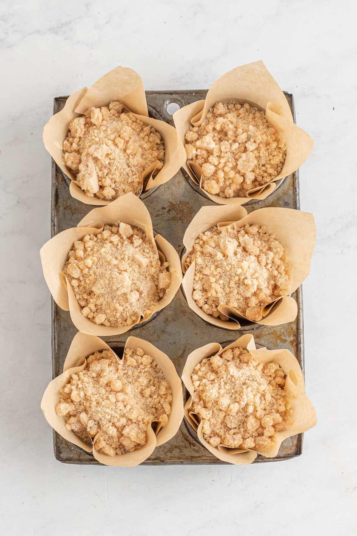 Muffins aux pêches avec streusel ajouté, pas encore cuits.