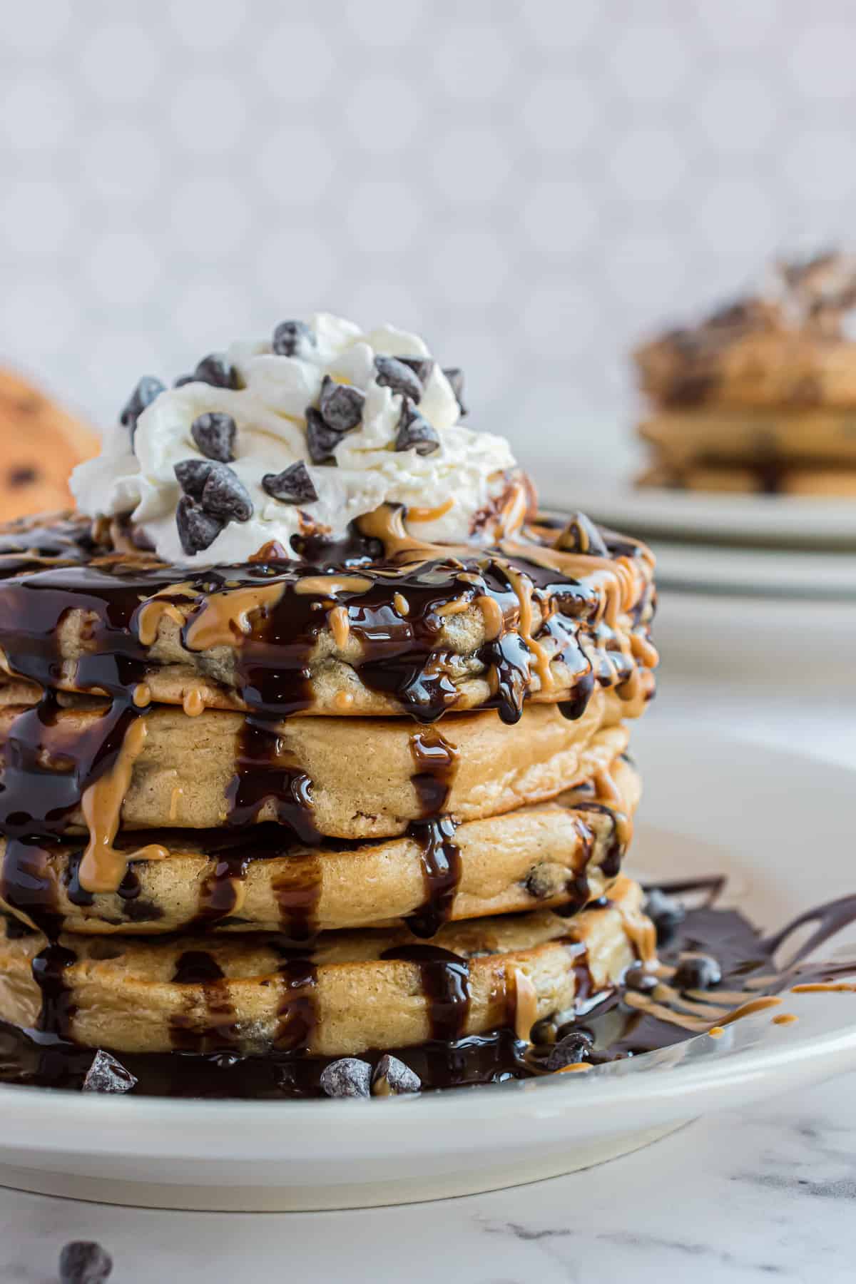 Pile de pancakes avec du sirop au chocolat et de la crème fouettée.