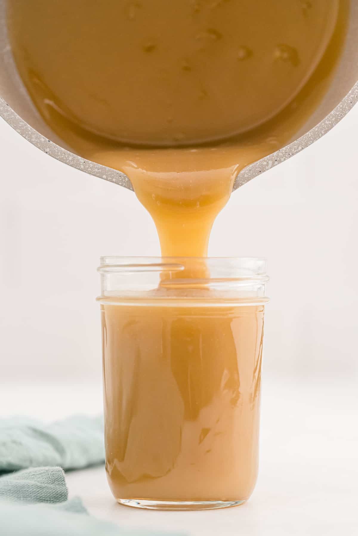 La sauce caramel étant versée d'une casserole dans un pot en verre.