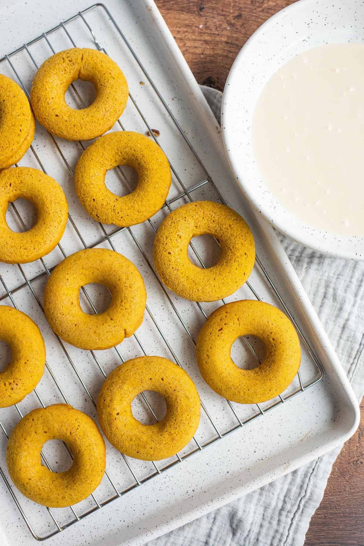 Les donuts cuits sur une grille de refroidissement, un bol de glaçage à côté.