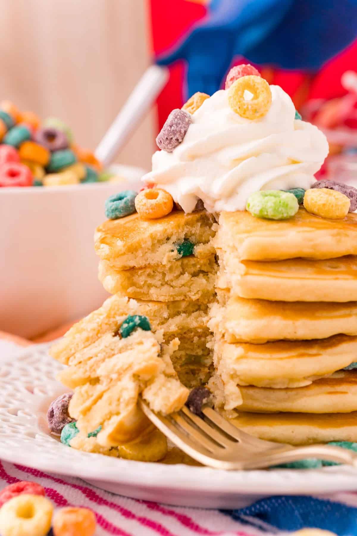 Pancakes aux Froot Loops dans une grande pile, une part coupée pour montrer la texture.