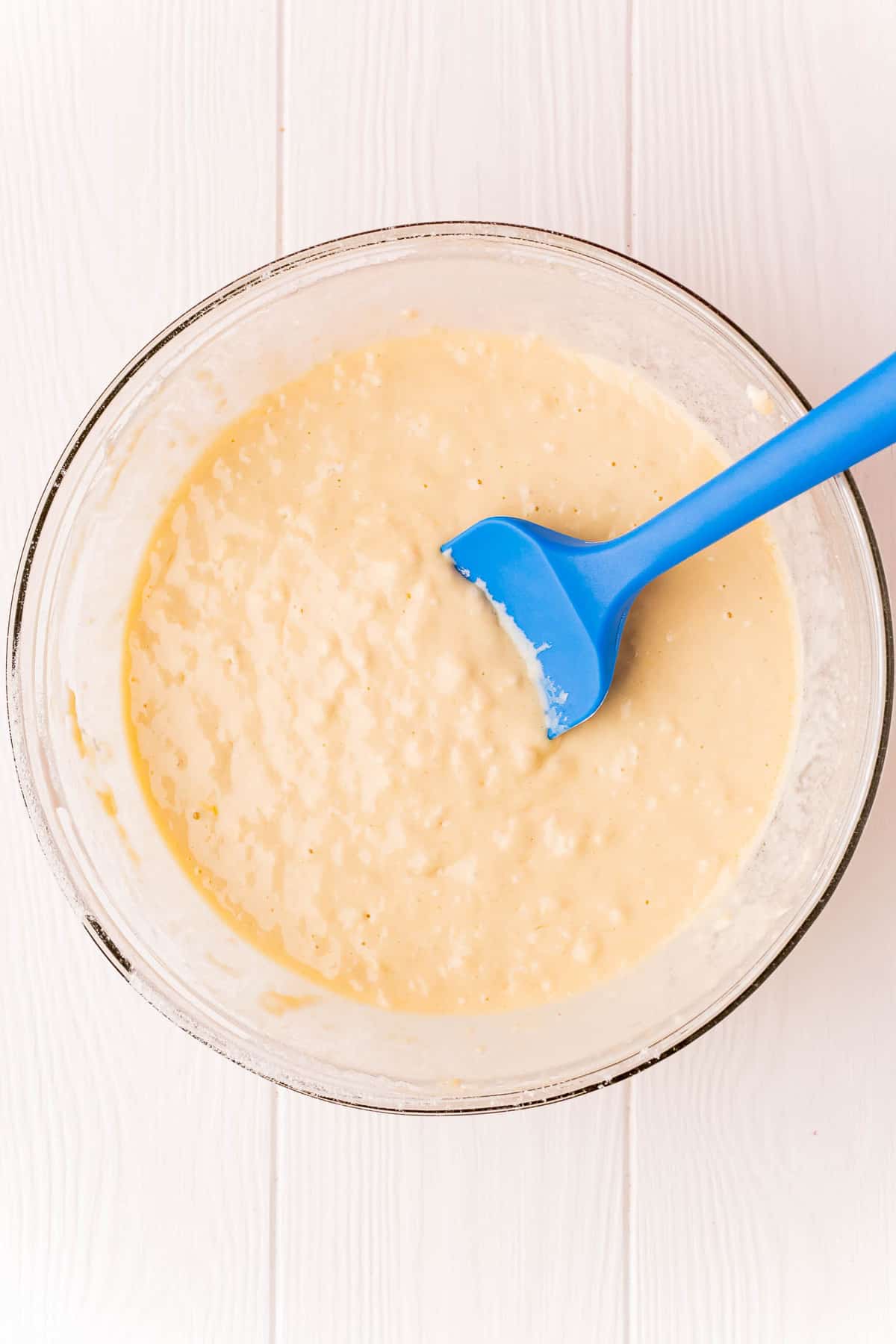 PĂąte Ă pancake dans un bol en verre avec une spatule bleue.