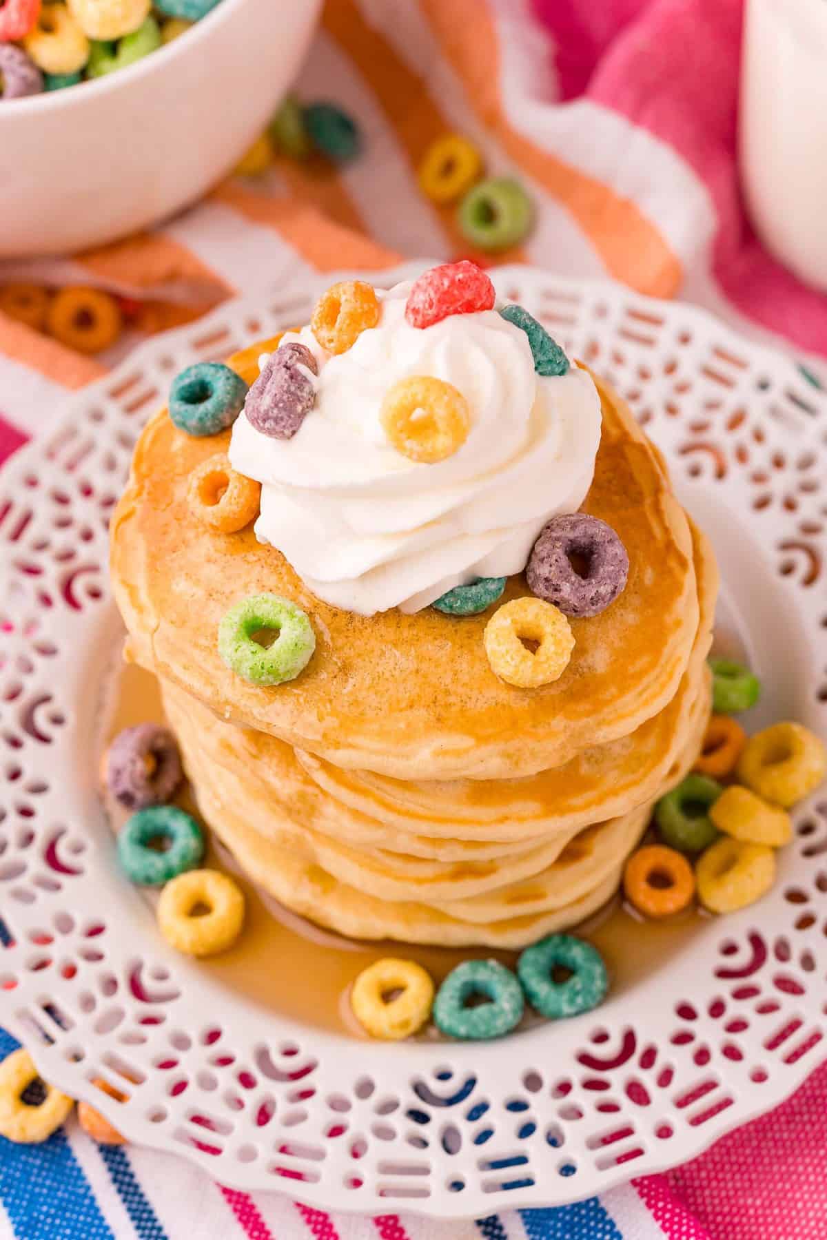 Vue d'ensemble d'une pile de pancakes garnis de Froot Loops et de crÚme fouettée.