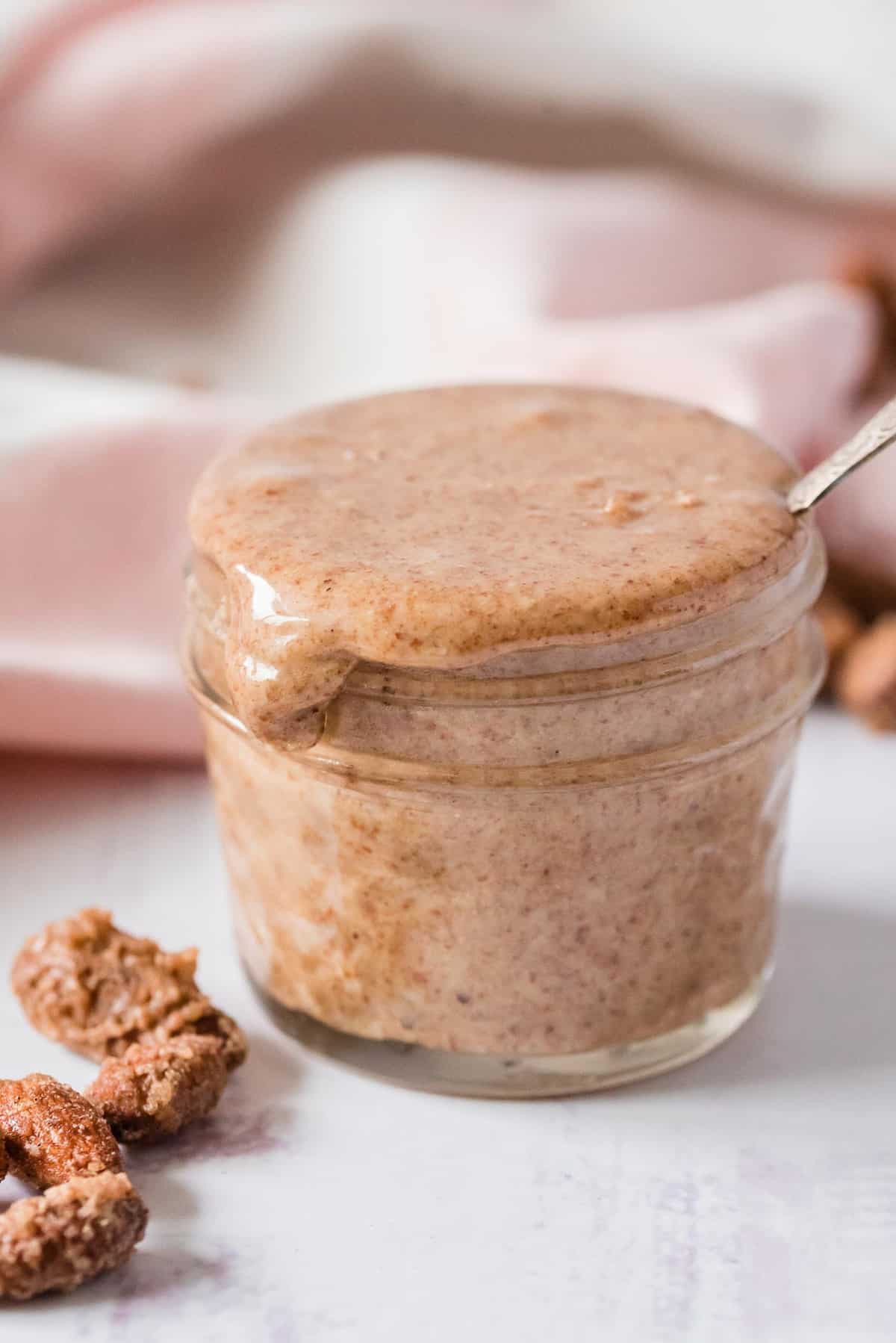Beurre d'amande débordant d'un petit pot en verre.