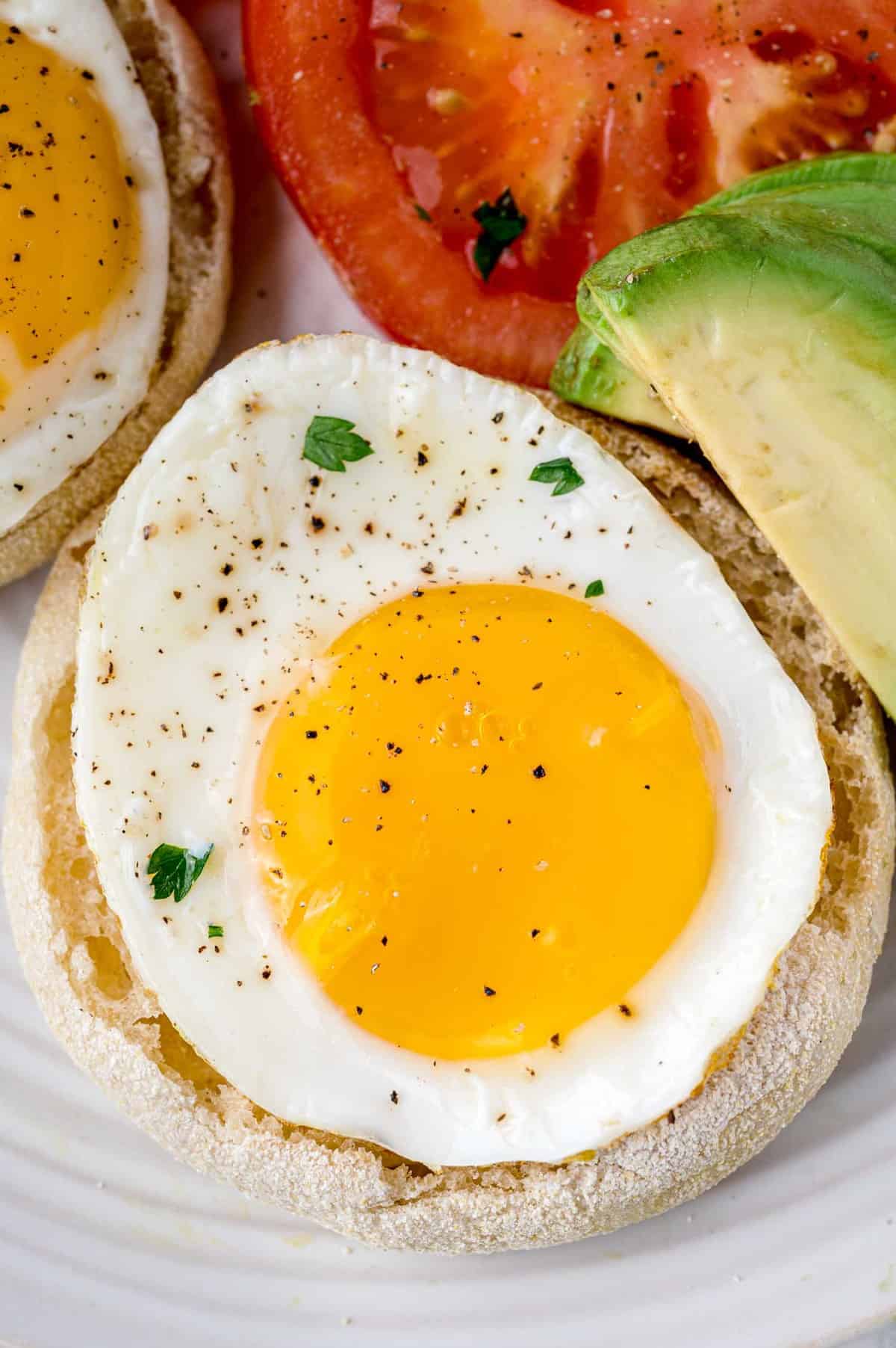 Œuf au plat sur une assiette avec avocat et tomate.
