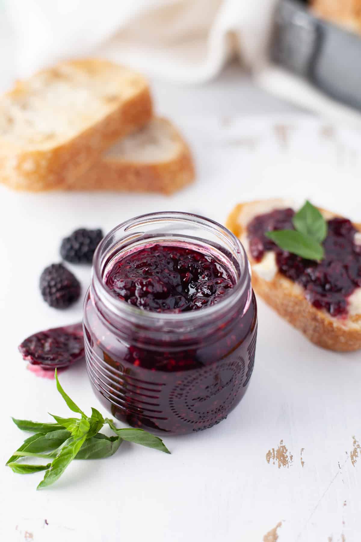 Confiture saine de fruits rouges dans un petit pot, avec du pain grillé à la confiture en arrière-plan.